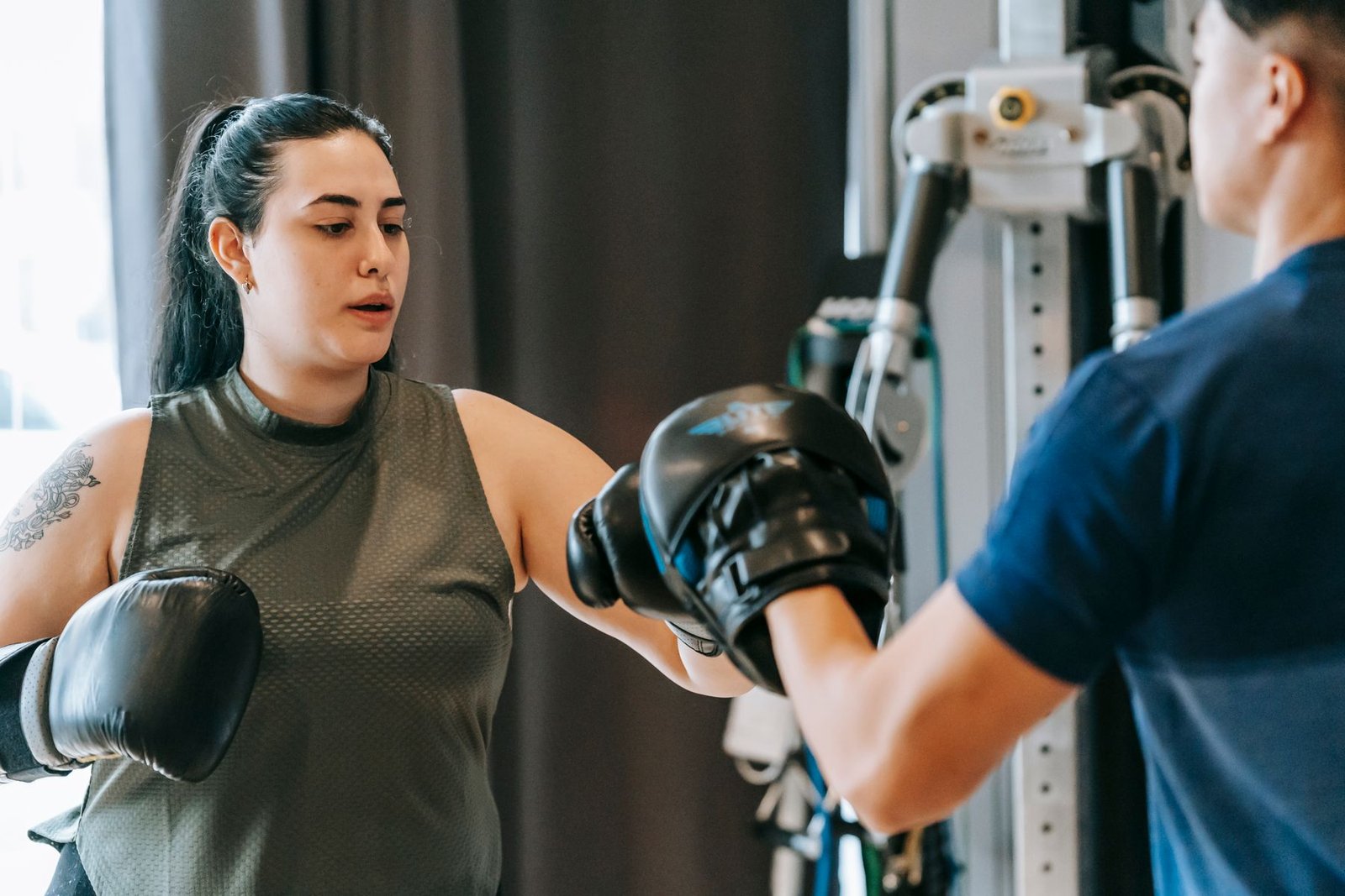 Une coach accompagne une sportive pendant un entraînement de boxe